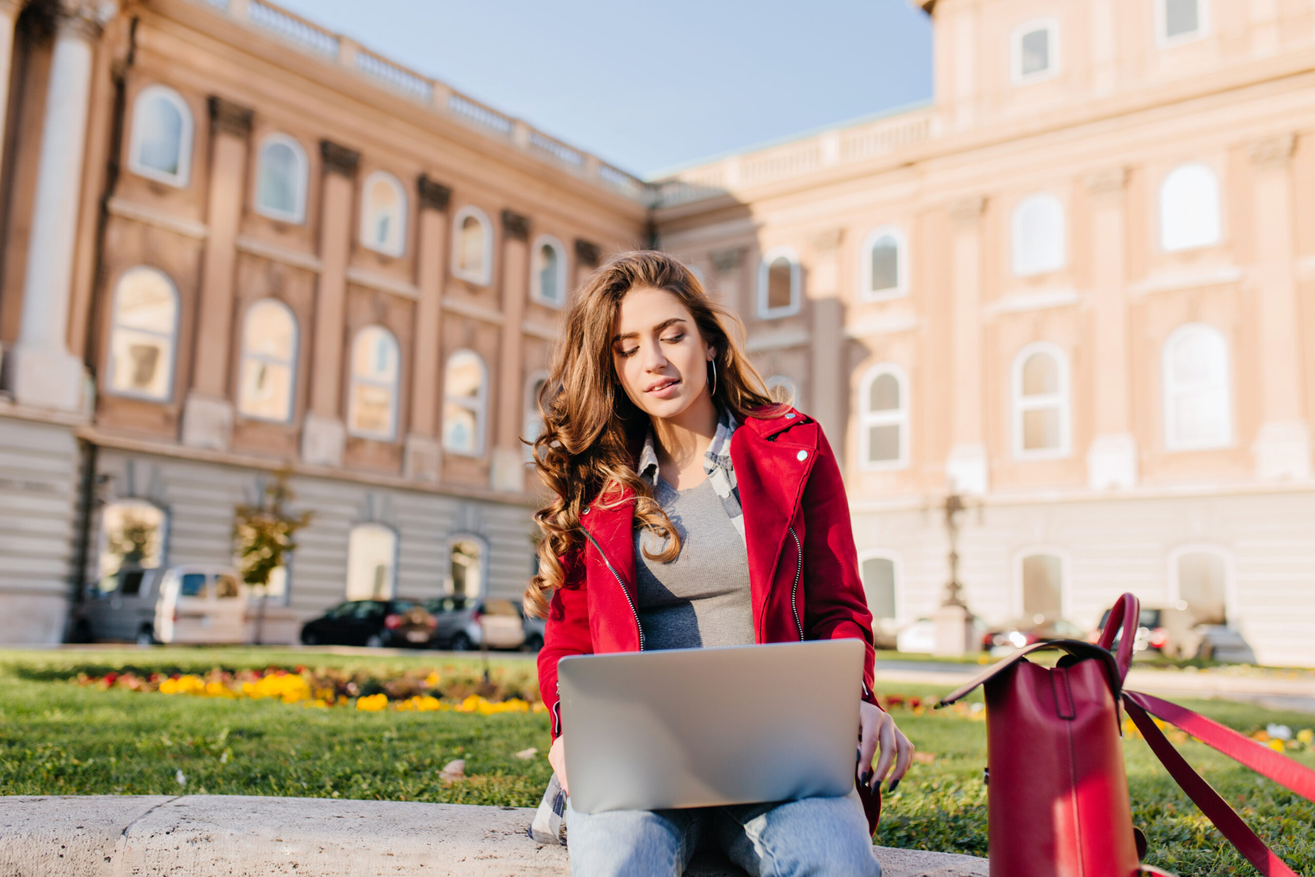 outdoor portrait serious curly female student sitting with laptop ground scaled